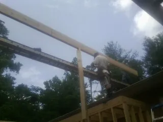 Carpenter setting a ridge beam over a new addition frame — Ice Dam Removal by Roofing Brothers in Hugo