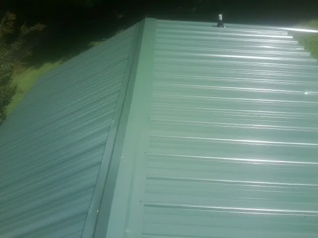 New green metal panels meeting at the ridge of a roof — Flat Roof Repair work by our crew in Hugo